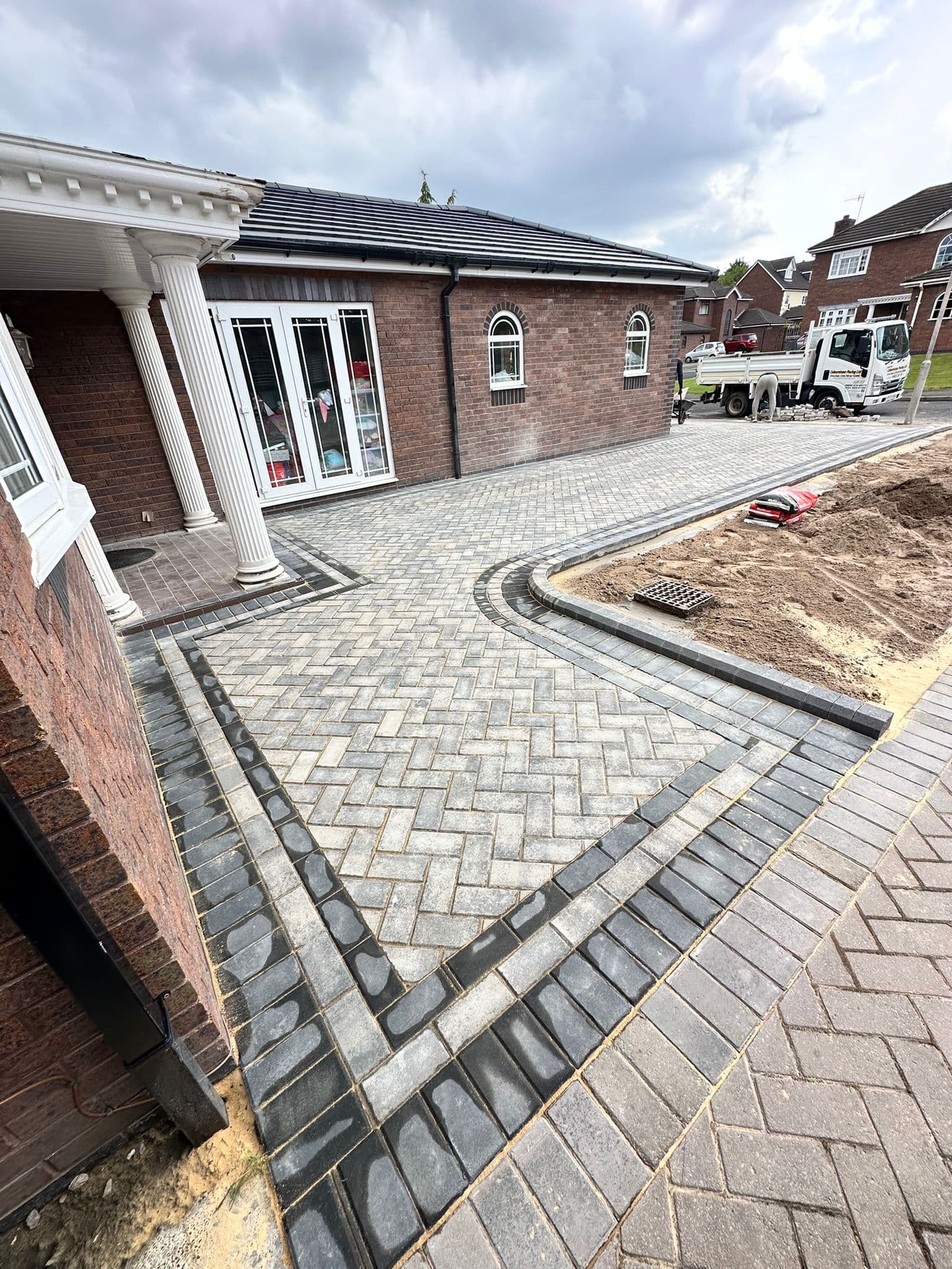 Block paved driveway laid in a herringbone pattern with a contrasting border