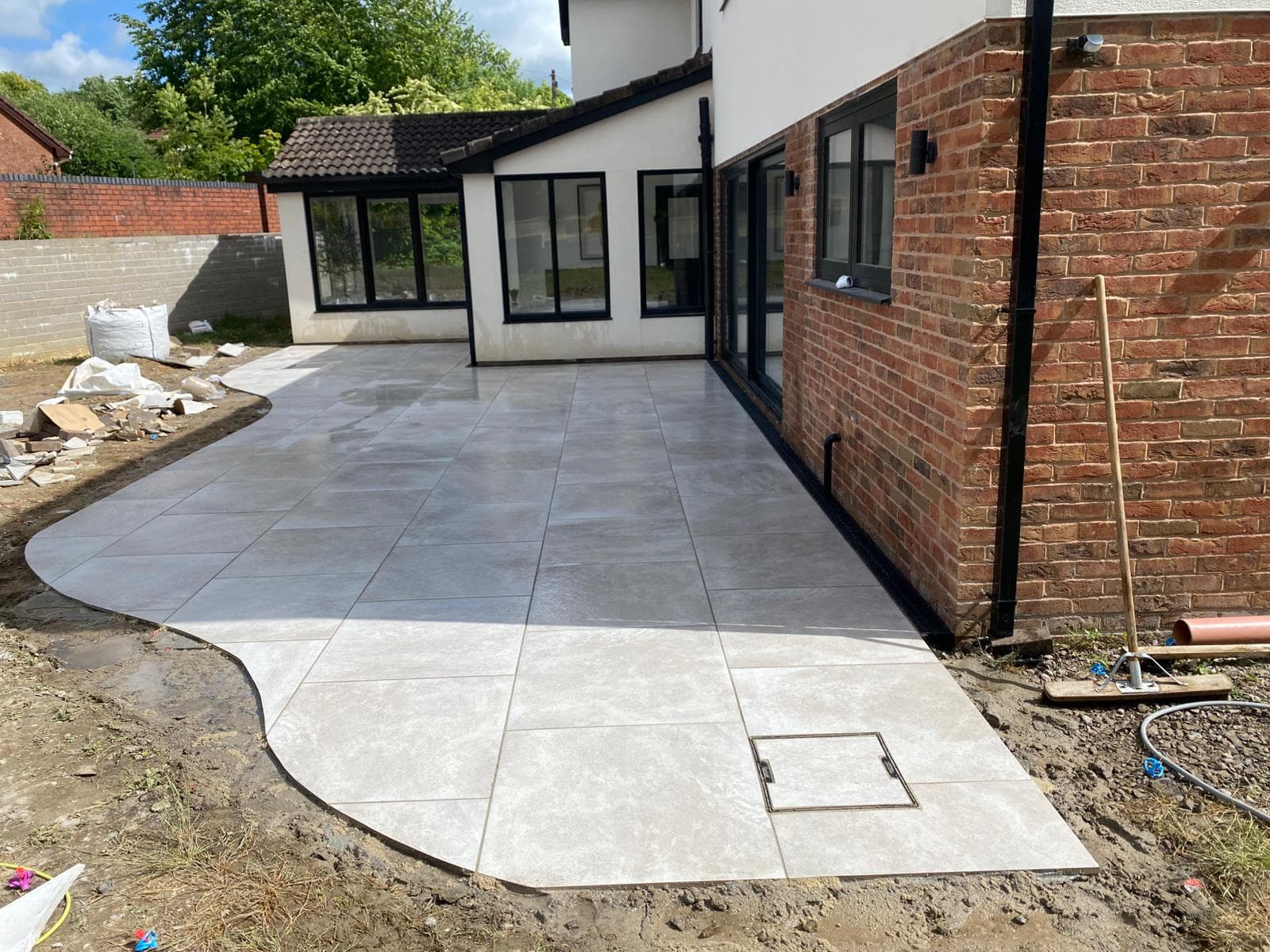 Grey porcelain patio laid across the rear of a house