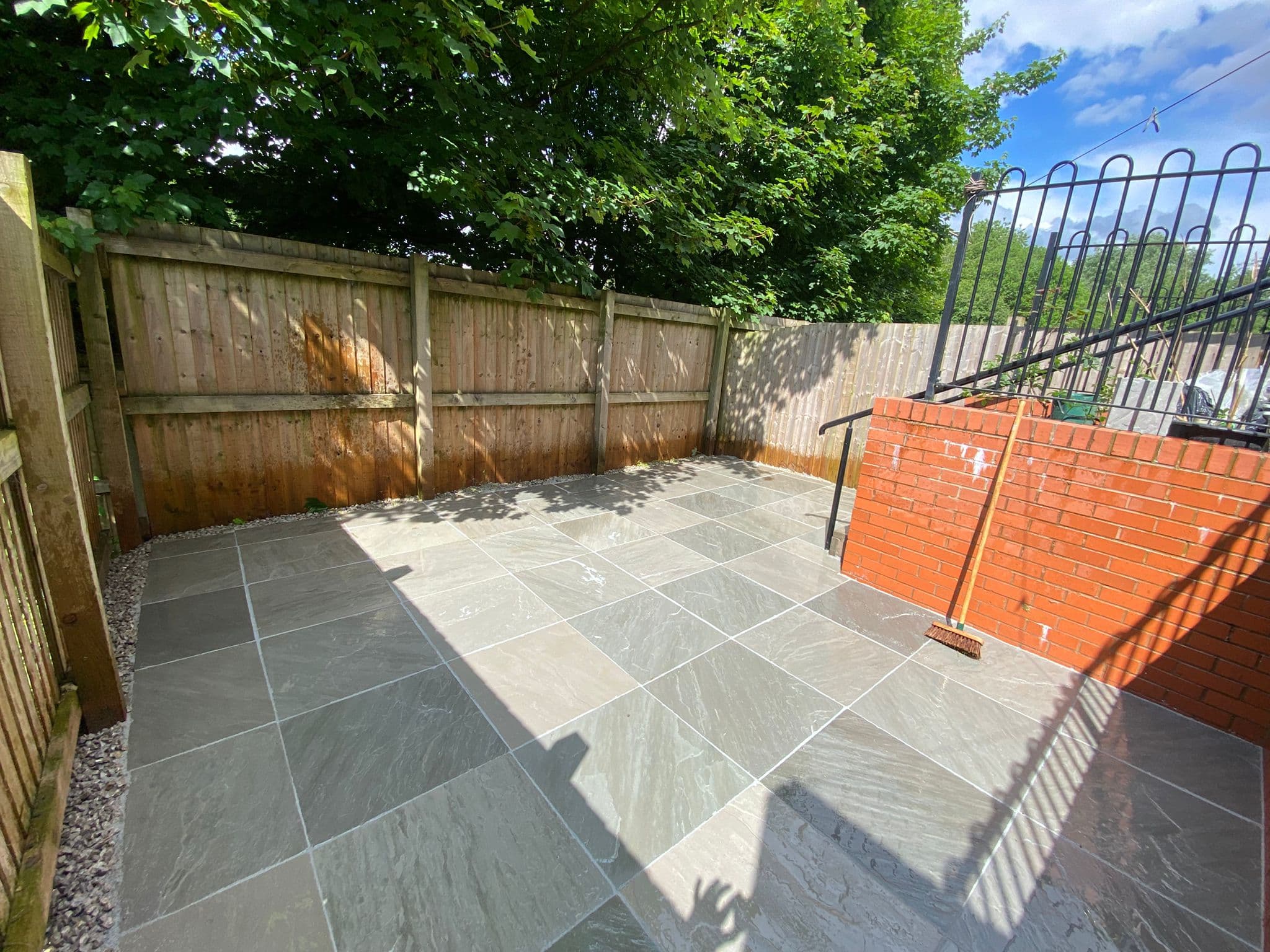 Grey Indian sandstone patio finished up to a garden boundary